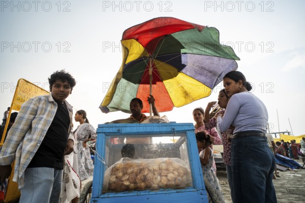 GUWAHATI, INDIA - APRIL 5: A vendor sells panipuri as he stand under a large umbrella during a pre monsoon storm in Guwahati, India on April 5, 2025