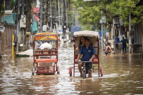 Commuters in cycle rickshaws as they wade through a flooded street after heavy rains in Guwahati, India on April 28, 2025