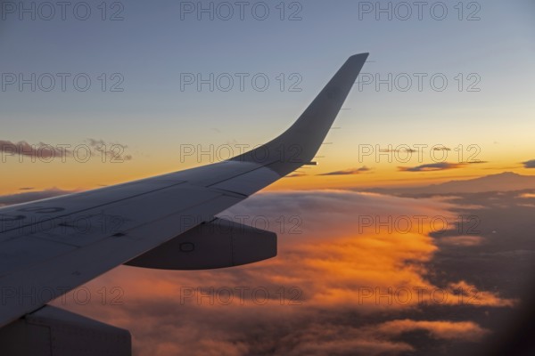 Mexico City, An AeroMexico Connect Embraer jet flies over orange clouds as it approaches Mexico City