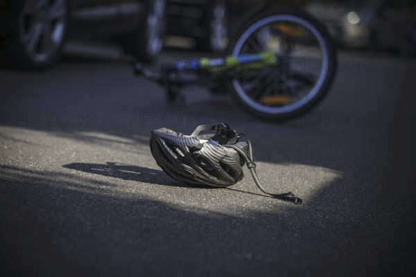 Symbol photo on the subject of bicycle accidents (posed scene) . A broken bicycle helmet lies next to a bicycle on a road Berlin, 21/08/2024