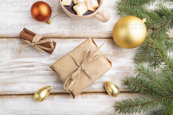 Christmas or New Year composition. Decorations, box, golden balls, cinnamon, fir and spruce branches, cup of coffee, on a white wooden background. Top view, close up, flat lay