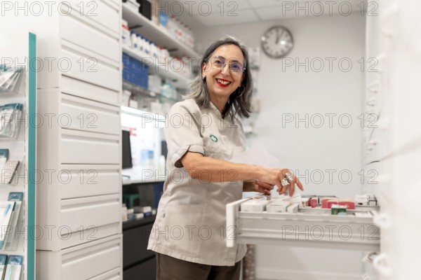 Side view photo of a woman cheerful pharmacist smiling while working in the storage room