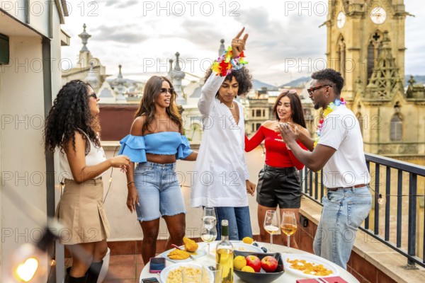 Young man dancing with multi-ethnic friends in rooftop during birthday party