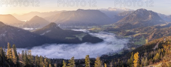 Panoramic photo. View from Mount Loser to Lake Altaussee, Altaussee, Bad Aussee, Tressenstein, Zinken, Sarstein, Dachstein mountains. Wafts of mist over the lake. In the morning at sunrise. Blue sky. Autumn, yellow larches. Altaussee, Bad Aussee, Ausseer Land, Totes Gebirge, Styria, Upper Austria, Austria, Europe