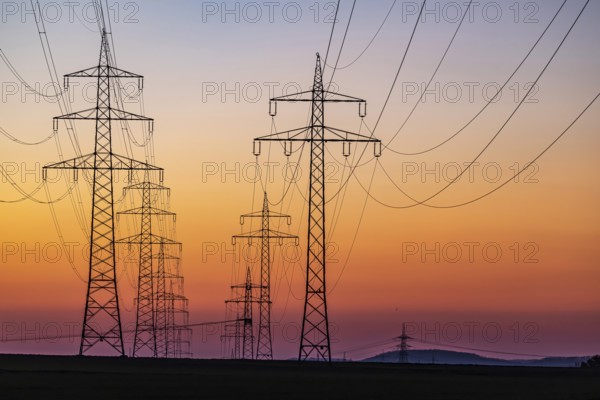 High-voltage pylons, overhead power lines at sunset. Schwieberdingen, Baden-Württemberg, Germany, Europe
