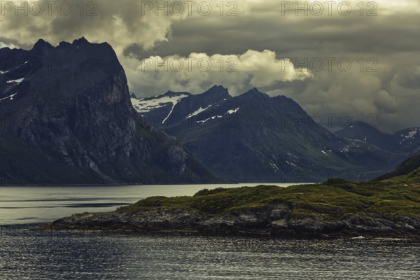 Dramatic mountain silhouette under dark clouds with a calm lake, Norway, Europe