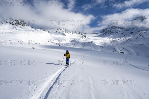 Ski tourer ascending through picturesque snow-covered mountain landscape with views of mountain peaks, ascent to the Chamanna Es-cha mountain hut, Bündner Haute Route ski tour, Albula Alps, Rhaetian Alps, Grisons, Eastern Switzerland, Switzerland, Europe