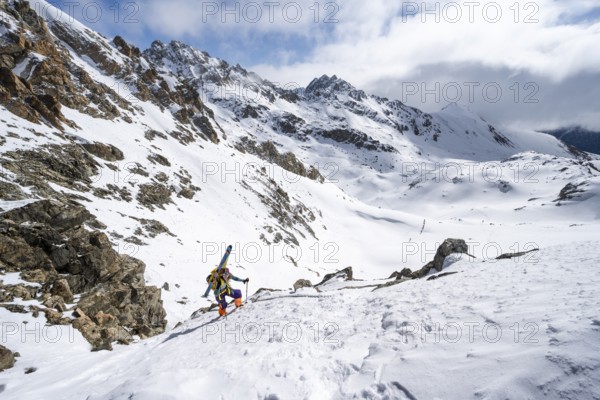Mountaineer with skis climbing up a steep snow slope to the fork Porta d'Es-cha, ski tour Bündner Haute Route, Albula Alps, Rhaetian Alps, Grisons, Eastern Switzerland, Switzerland, Europe