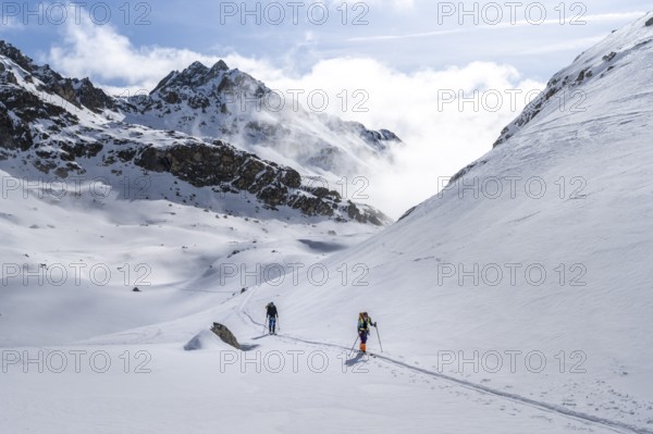 Atmospheric clouds in a wintry mountain landscape, ski tourers on the ascent to Porta d'Es-cha, Grisons Haute Route ski tour, Albula Alps, Rhaetian Alps, Grisons, Eastern Switzerland, Switzerland, Europe
