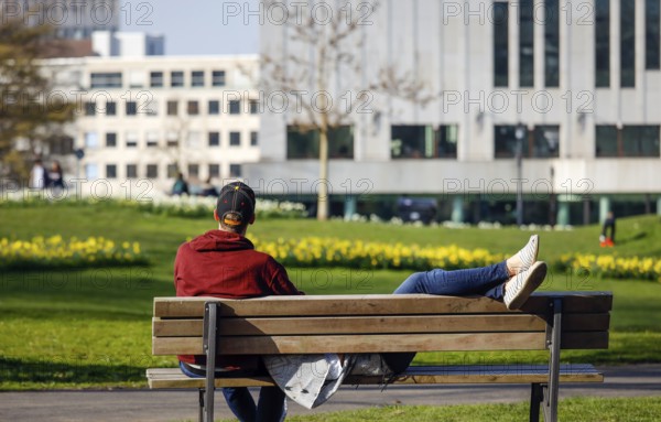 A couple relaxing on a park bench in the city garden in times of the corona crisis, Essen, Ruhr area, North Rhine-Westphalia, Germany, Europe