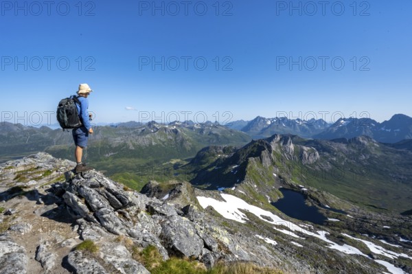View of mountain landscape, mountain panorama, mountaineer at the summit of Rundfjellet, lake Hellskarvatnet, Svolvaer, Nordland, Norway, Europe