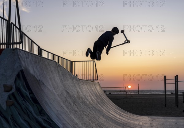 Skater, scooter in a halfpipe at the beach of Scheveningen, sunset, Netherlands