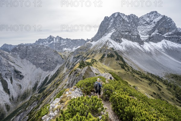 Mountaineers on a hiking trail on the ridge of Hahnkampl, mountain panorama with rocky steep peaks, view of summit Lamsenspitze, in autumn, Karwendel Mountains, Alpenpark Karwendel, Tyrol, Austria, Europe
