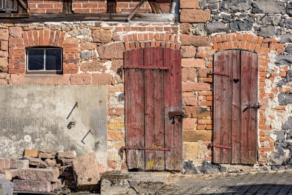 Historic farmhouse around 1800, half-timbered façade, sandstone, natural stone, brick, cement, weathered wooden doors to stable and loo, with heart, idyllic, romantic, Nidda, Vogelsberg, Wetterau, Hesse, Germany, Europe