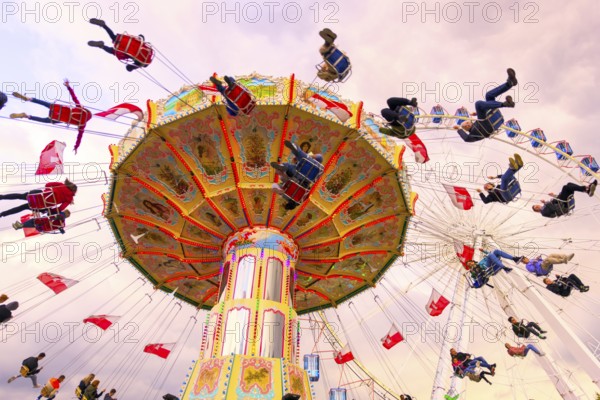 Chain carousel in motion with cheerful people in front of a cloudy sky, Ferris wheel, wave flight, Cannstadter Volksfest, Stuttgart, Baden-Württemberg