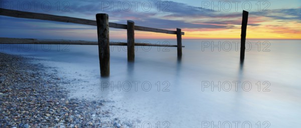 Sunset at Darßer Ort, fence and posts on the Baltic Sea as the border of the cordoned-off core zone of the Vorpommersche Boddenlandschaft National Park, pebbles on the beach, Weststrand, Darß peninsula, Fischland-Darß-Zingst, Mecklenburg-Western Pomerania, Germany, Europe