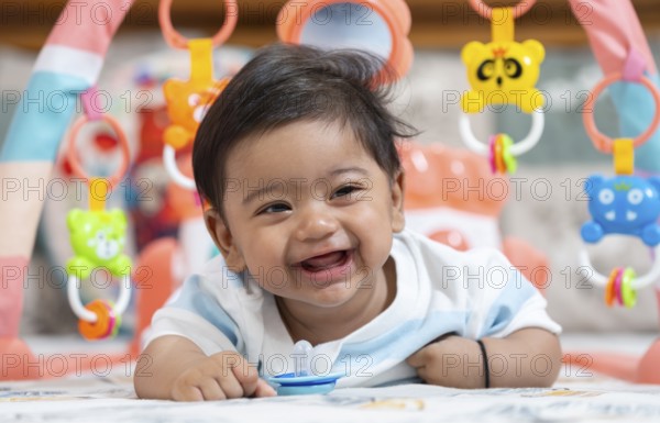 Baby boy playing and smiles lying on bed with pacifier on mouth