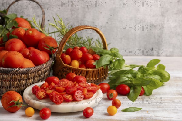 Sliced tomatoes on a white marble slab, surrounded by fresh tomatoes in baskets and herbs