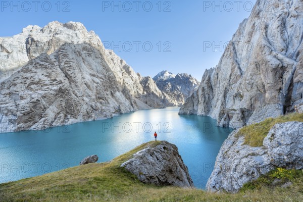 Young man at the turquoise mountain lake Kol Suu with rocky steep mountains, Kol Suu Lake, Sary Beles Mountains, Naryn Province, Kyrgyzstan, Asia