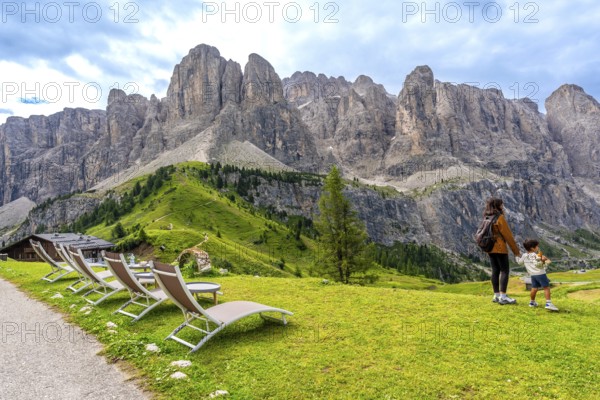 Tourists enjoying the breathtaking view of the dolomites mountain range at gardena pass during a sunny summer day in italy