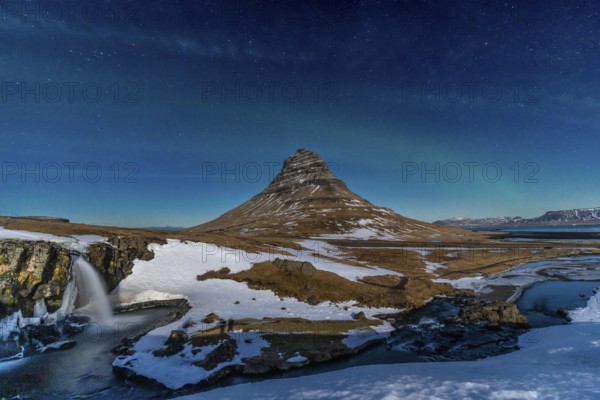 Long exposure of Kirkjufell snowy mountain and its beautiful waterfall in Icelandic winter