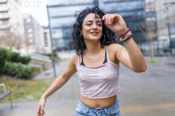 Carefree young latin woman enjoying dancing outdoors in urban environment, expressing joy and freedom