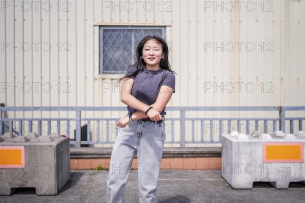 Happy vital young asian woman gesturing while dancing k-pop choreography in the city