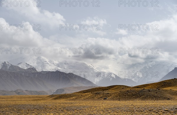 Glaciated, cloud-covered mountain peaks and golden meadows, Lenin Peak, Trans Alay Mountains, Pamir Mountains, Osh Province, Kyrgyzstan, Asia