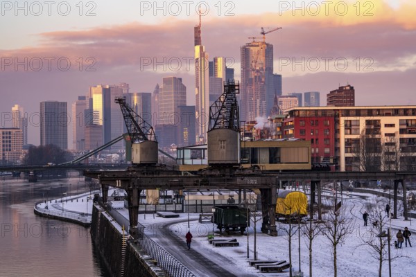 The skyline of Frankfurt am Main, skyscrapers of the banking district, historic harbour cranes at the Wesel shipyard, wintry morning, Hesse, Germany, Europe