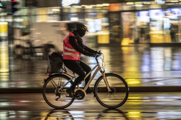 Street at the central station, cyclist, rainy weather, city centre, in the evening, Essen, North Rhine-Westphalia, Germany, Europe