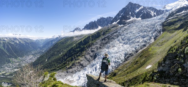 Mountaineer standing on a rock, mountain landscape with glacier Glacier des Bossons and summit of Aiguille du Midi, Chamonix, Haute-Savoie, France, Europe