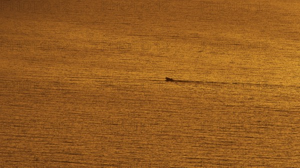 Small boat sails through the calm orange sea at sunset, Kritinia Castle, St John's Castle, Kritinia, Rhodes, Dodecanese, Greek Islands, Greece, Europe