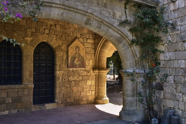 Monastery of Our Lady of Mount Filerimos, A stone archway of a medieval church with a dark door, icon and climbing plants in the sunlight, Filerimos, hill not far from Rhodes Town, Ancient State of Ialyssos, Rhodes, Dodecanese, Greek Islands, Greece, Europe