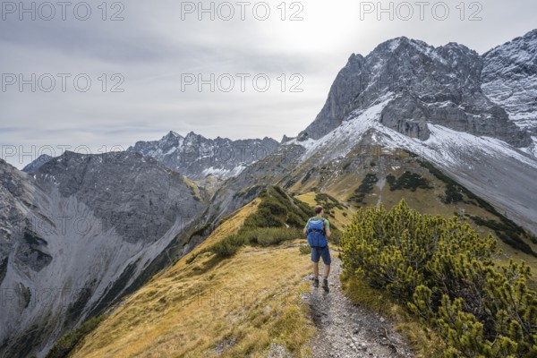 Mountaineers on a hiking trail on the ridge of Hahnkampl, mountain panorama with rocky steep peaks, view of summit Lamsenspitze, in autumn, Karwendel Mountains, Alpenpark Karwendel, Tyrol, Austria, Europe
