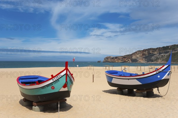 Two fishing boats on the sandy beach of Nazaré with a view of the sea and the cliffs, Praia da Nazare beach, Nazaré, Oeste, Leiria district, Centro, Extremadura, Portugal, Europe