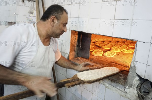A baker puts the bread in the oven, Barbol, Iran, 18/05/2016, Asia
