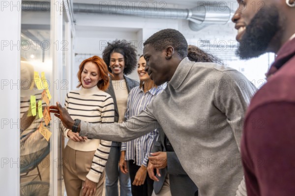African man participating in a brainstorming process in a startup standing with colleagues at the coworking