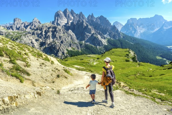 Tourists enjoying breathtaking mountain view while hiking in the italian alps during summer vacation
