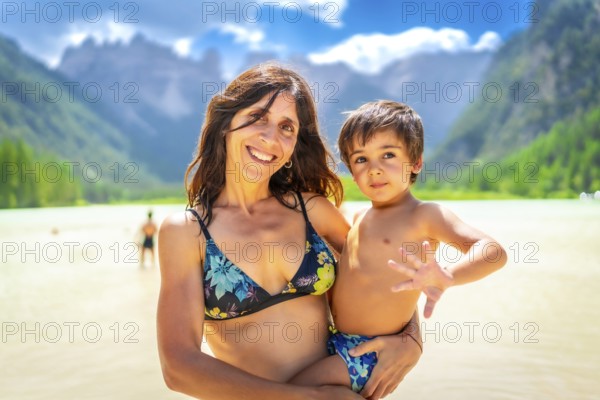 Mother holding her son while enjoying a swim in the beautiful lago di landro in the italian dolomites during summer