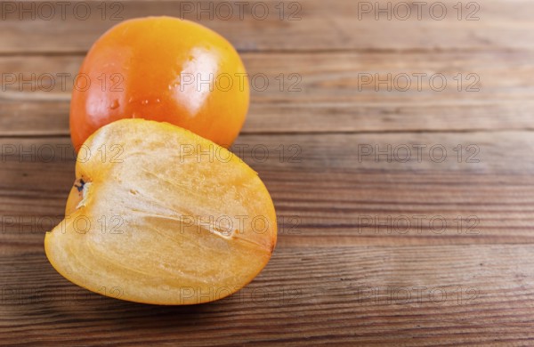 Ripe orange persimmon on brown wooden background, with copy space