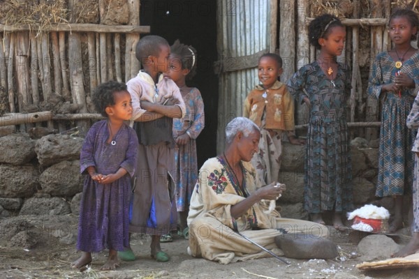 Amhara region, simple family, small farm, children, woman sitting on the ground plucking cotton, Ethiopia, Africa