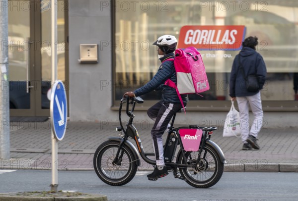 Bicycle courier of the fast delivery service Flink, delivers groceries, currently in over 40 German cities, within 10 minutes, orders via an app, works together with the REWE Group, in the background competitor Gorillas, Bochum, North Rhine-Westphalia, Germany, Europe