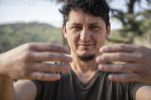 Close-up of a Caucasian adult man practicing the static posture of Tree Hugging, an essential technique in Chi Kung practice. Selective focus