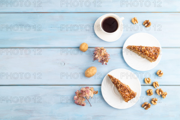 Walnut and hazelnut cake with caramel cream, cup of coffee on blue wooden background. top view, flat lay, copy space