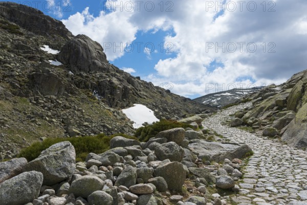 A stony path through a rocky mountain region with patches of snow under a cloudy sky, hiking area, Reserva national de Gredos, Garganta de Prado Puerte, Prado Puerte Gorge, Sierra de Gredos, Ávila, Avila, Madrid, Spain, Europe
