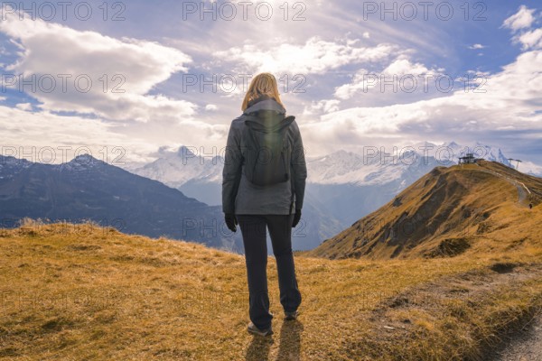 A person looks into the distance, surrounded by mountains under a dramatically cloudy sky, Planplatten, Switzerland, Europe
