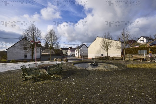 Village fountain, benches, lantern, trees, houses, blue sky, cumulus clouds, cirrostratus clouds, street Im Höfchen and main street, Dreis-Brück, Eifel, district Vulkaneifel, Rhineland-Palatinate, Germany, Europe
