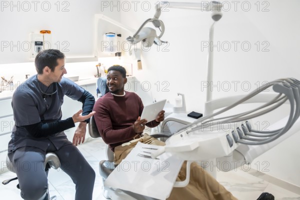 Dentist discussing treatment plan with patient using digital tablet in modern dental clinic, showcasing advanced technology and patient care