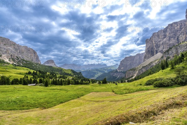 Stunning landscape of the italian dolomites, featuring the gardena pass winding through lush valleys and majestic peaks under dramatic clouds