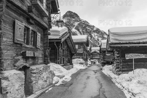 Street with historic old snow-covered wooden houses, black and white photo, mountain village Zinal, Val d'Anniviers, Valais Alps, Canton Valais, Switzerland, Europe